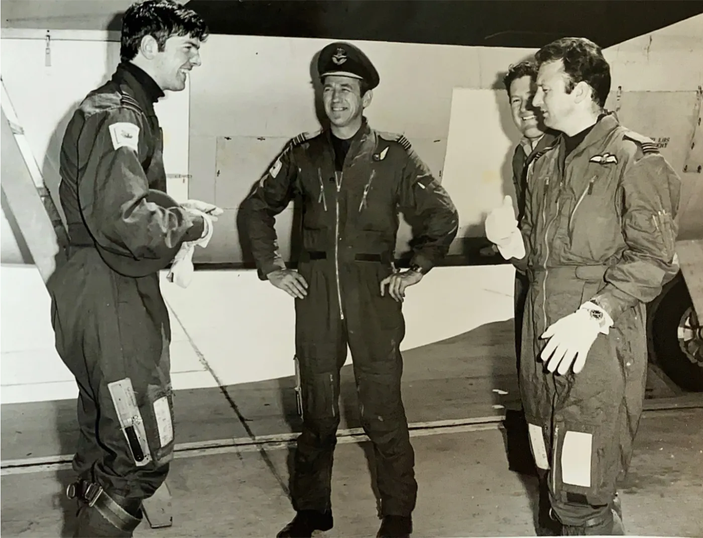 Four aircrew in flying suits talking beside an aircraft