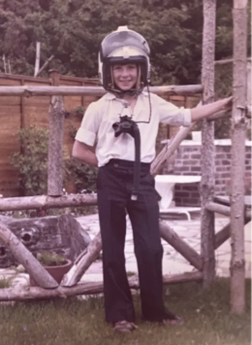 A child wearing a flying helmet in a garden